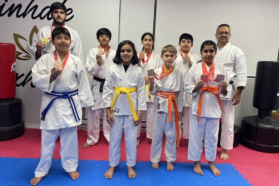 Students and instructors from Yogi’s Karate Dojo proudly displaying their medals after earning 11 awards in a karate competition.