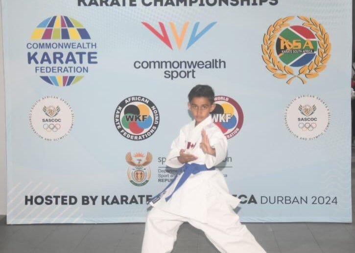 A young karate student wearing a blue belt and representing Canada poses proudly at the Commonwealth Sport event.